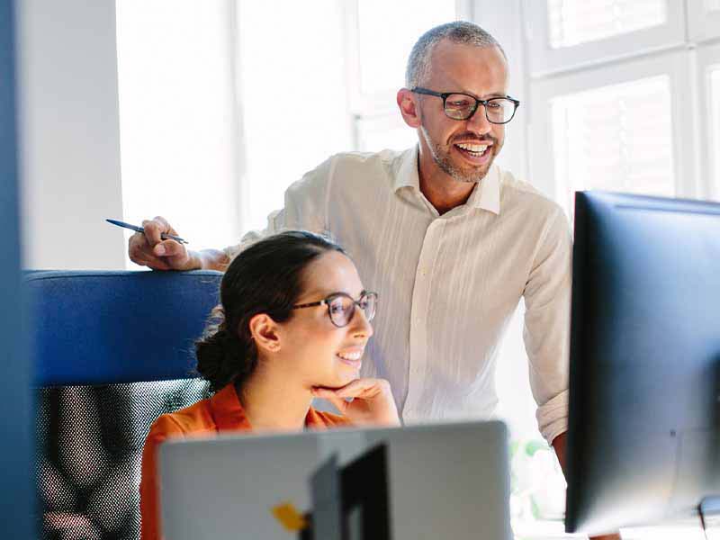 Man and woman looking at computer screen together in an office.